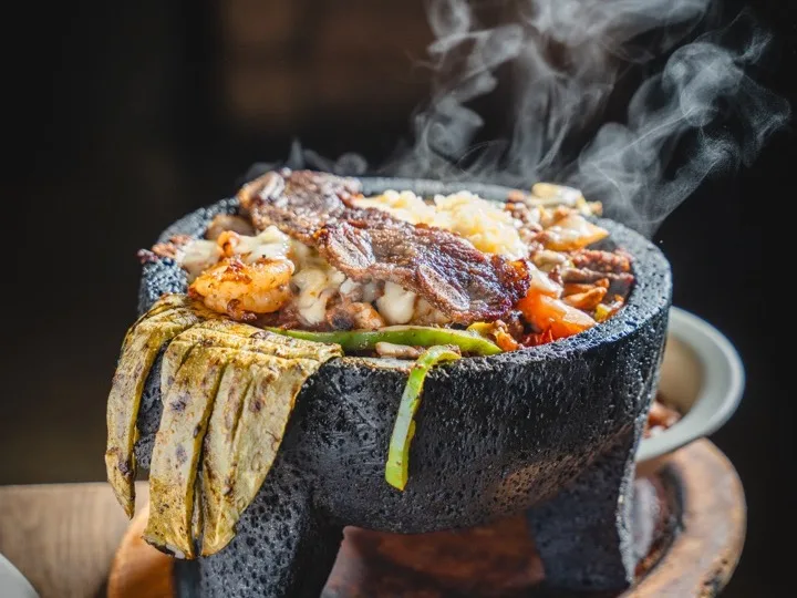 Molcajete bubbling with grilled meats over cactus